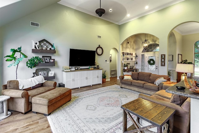 living room featuring crown molding, light hardwood / wood-style floors, and high vaulted ceiling