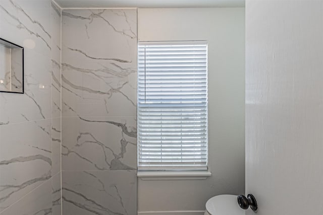 bathroom featuring tiled shower and toilet