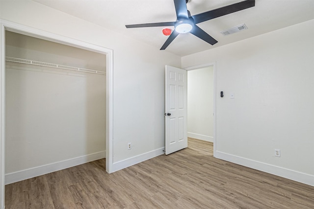 unfurnished bedroom featuring ceiling fan, a closet, and light wood-type flooring