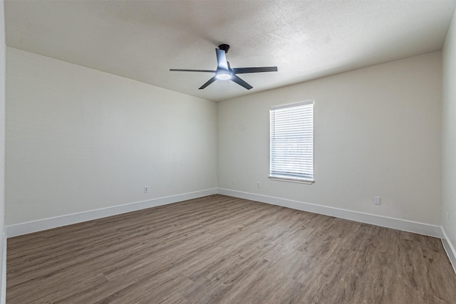 empty room with ceiling fan, wood-type flooring, and a textured ceiling