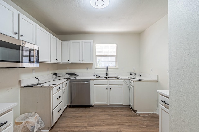 kitchen with sink, white cabinets, appliances with stainless steel finishes, and hardwood / wood-style floors