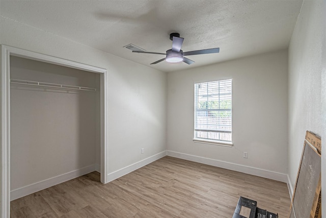 unfurnished bedroom featuring ceiling fan, light hardwood / wood-style floors, a textured ceiling, and a closet