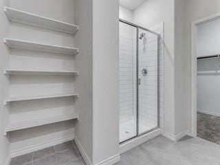 bathroom with a stall shower, tile patterned flooring, and baseboards