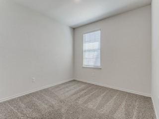 spare room featuring light carpet and baseboards