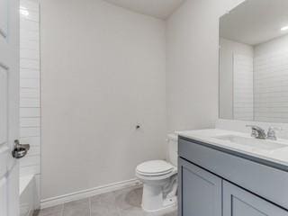 full bath with toilet, tile patterned floors, baseboards, and vanity