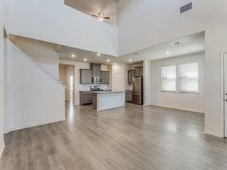 unfurnished living room with hardwood / wood-style flooring and a towering ceiling