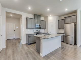 kitchen featuring sink, an island with sink, stainless steel appliances, light stone countertops, and light hardwood / wood-style floors