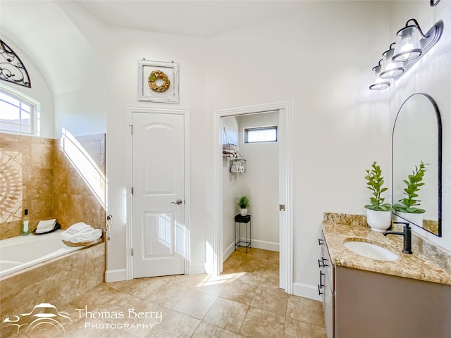 bathroom featuring tiled tub, vanity, a healthy amount of sunlight, and tile patterned floors