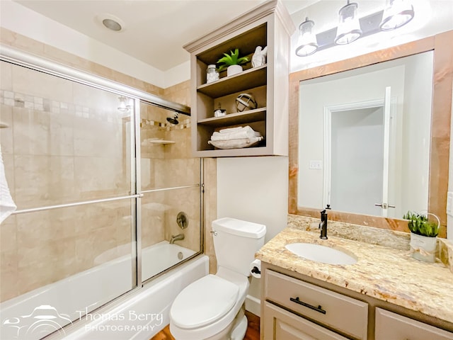 full bathroom featuring bath / shower combo with glass door, vanity, and toilet