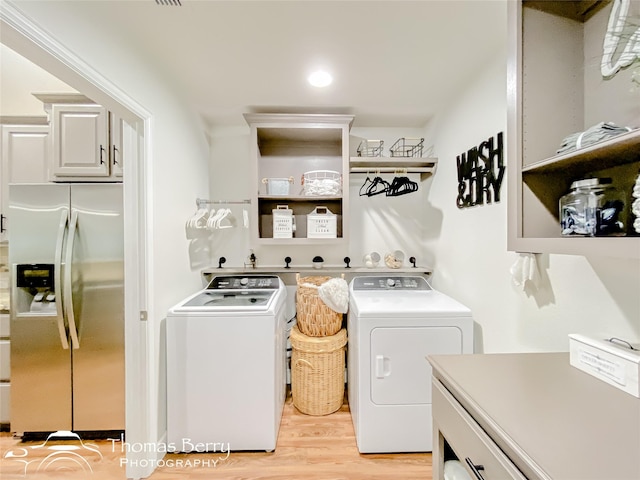 laundry room featuring separate washer and dryer and light hardwood / wood-style flooring