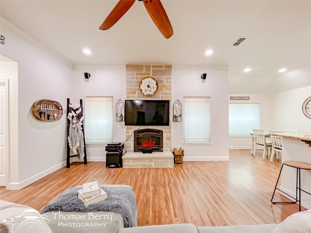 living room featuring hardwood / wood-style flooring, ceiling fan, and a fireplace