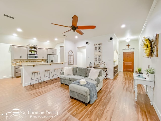 living room featuring ceiling fan, ornamental molding, and light hardwood / wood-style floors