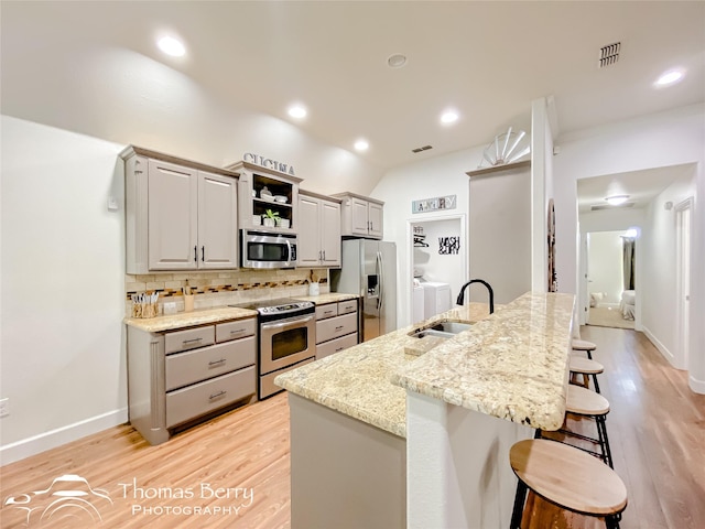 kitchen with a kitchen island with sink, sink, gray cabinets, and stainless steel appliances