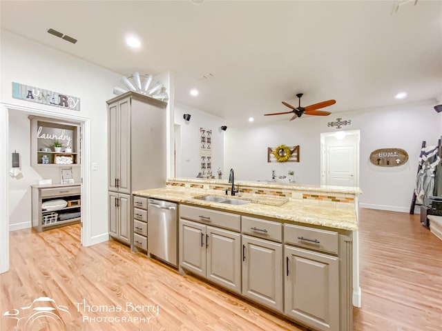 kitchen with sink, gray cabinetry, stainless steel dishwasher, light stone countertops, and light hardwood / wood-style flooring