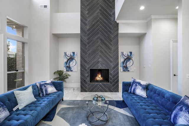 living room featuring crown molding and a large fireplace