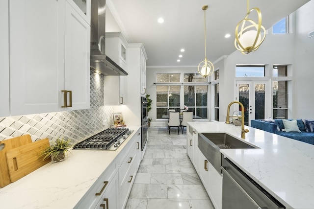 kitchen with stainless steel appliances, decorative light fixtures, white cabinetry, and wall chimney exhaust hood