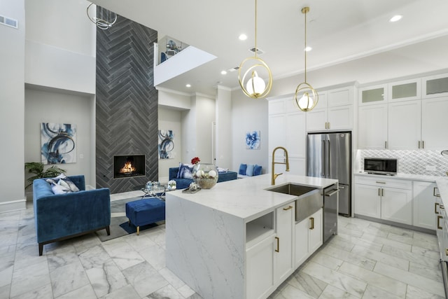 kitchen with light stone countertops, white cabinetry, a center island with sink, and stainless steel appliances