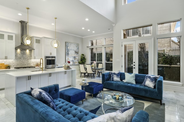 living room featuring sink, ornamental molding, french doors, and a healthy amount of sunlight