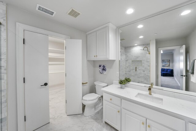 bathroom with a tile shower, vanity, and toilet