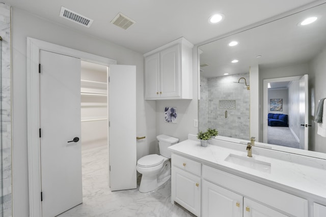 bathroom featuring a tile shower, toilet, and vanity