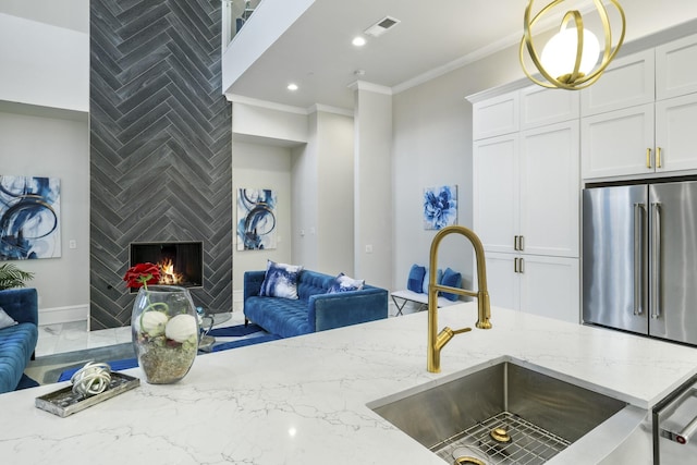 kitchen featuring sink, a large fireplace, ornamental molding, and light stone countertops