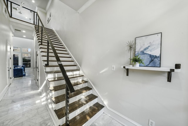 stairway featuring a high ceiling and ornamental molding