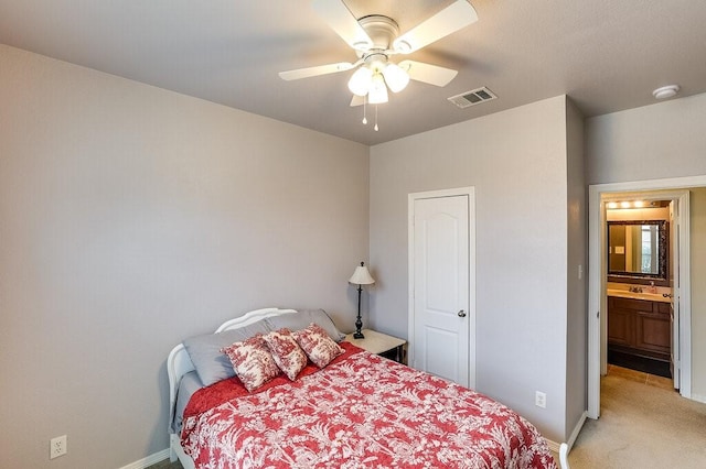 bedroom featuring connected bathroom, sink, light colored carpet, and ceiling fan