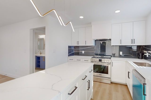 kitchen with sink, white cabinetry, light stone counters, stainless steel range with gas stovetop, and white dishwasher