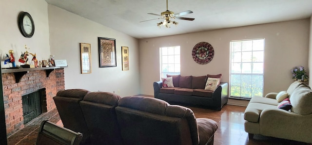 living room featuring ceiling fan, hardwood / wood-style floors, vaulted ceiling, and a fireplace