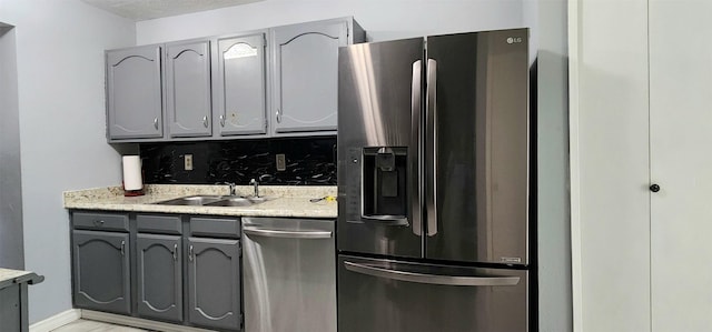 kitchen with sink, stainless steel appliances, gray cabinetry, and backsplash