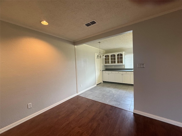 empty room with ornamental molding, light hardwood / wood-style floors, and a textured ceiling