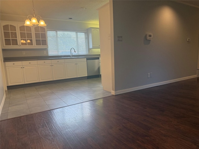 kitchen featuring white cabinetry, sink, hanging light fixtures, stainless steel dishwasher, and light hardwood / wood-style flooring