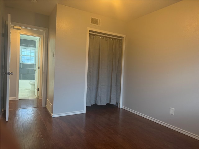 unfurnished bedroom featuring dark wood-type flooring and a closet