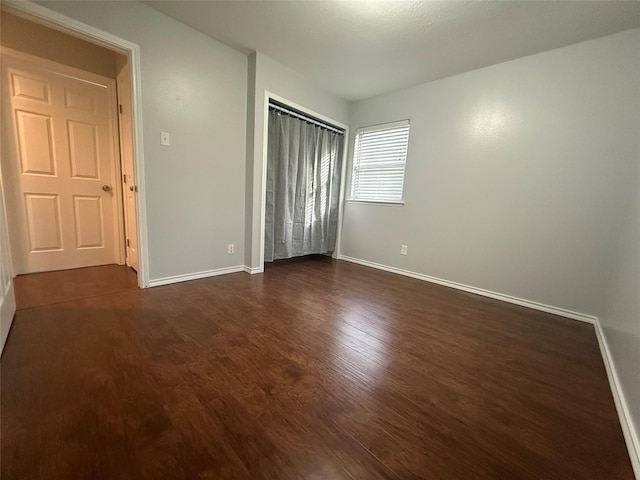 unfurnished bedroom featuring dark hardwood / wood-style flooring and a closet