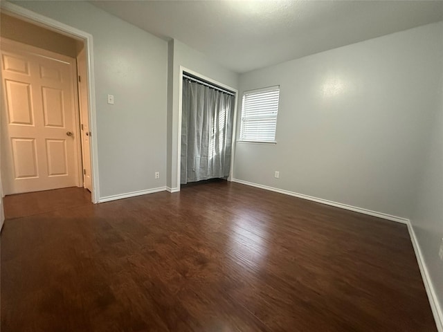 unfurnished bedroom featuring dark wood-type flooring and a closet