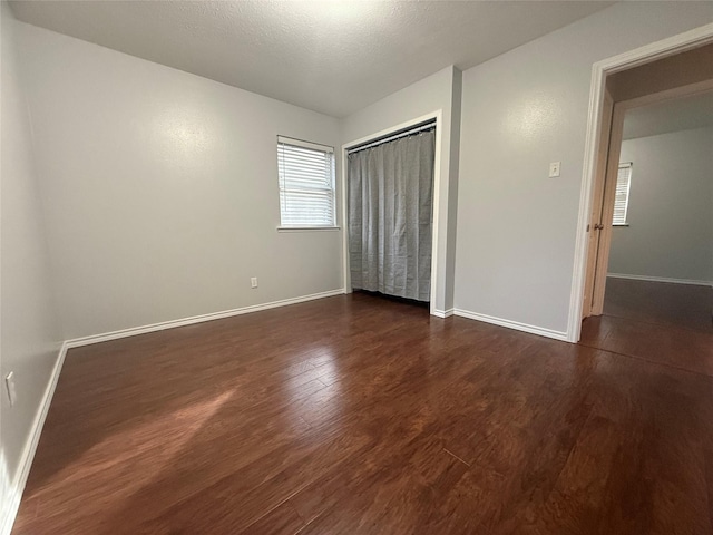 unfurnished bedroom with dark hardwood / wood-style floors, a textured ceiling, and a closet