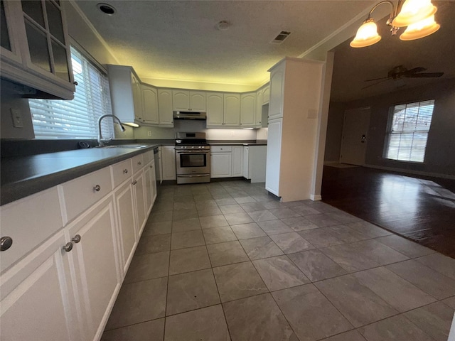 kitchen with sink, white cabinets, hanging light fixtures, stainless steel range oven, and tile patterned floors