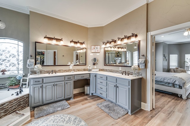 bathroom featuring a relaxing tiled tub, wood-type flooring, vanity, and ornamental molding