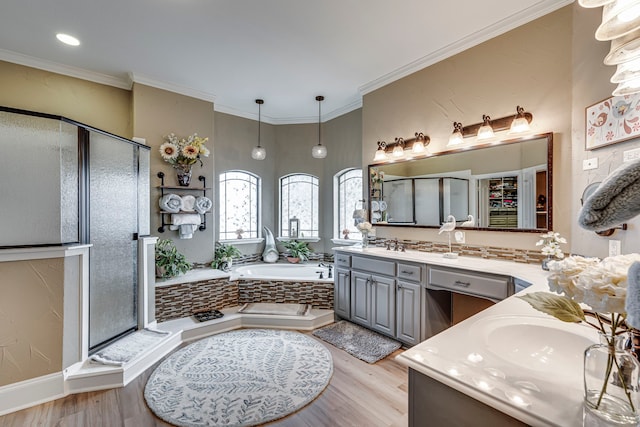 bathroom with crown molding, two vanities, a shower stall, a bath, and wood finished floors