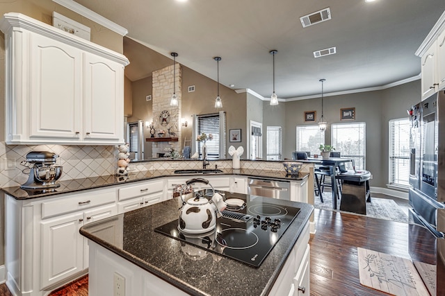 kitchen with white cabinetry, hanging light fixtures, black electric cooktop, sink, and kitchen peninsula