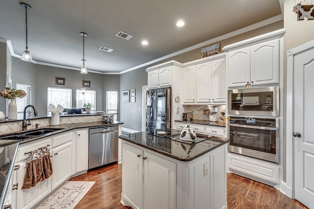 kitchen featuring appliances with stainless steel finishes, decorative light fixtures, sink, white cabinetry, and a center island