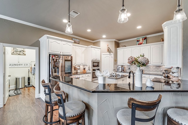 kitchen featuring a breakfast bar area, decorative light fixtures, white cabinetry, and appliances with stainless steel finishes