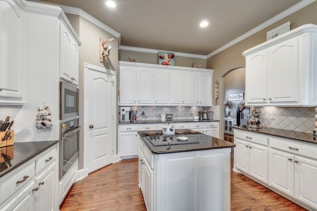 kitchen featuring stainless steel oven, backsplash, white cabinetry, and built in microwave