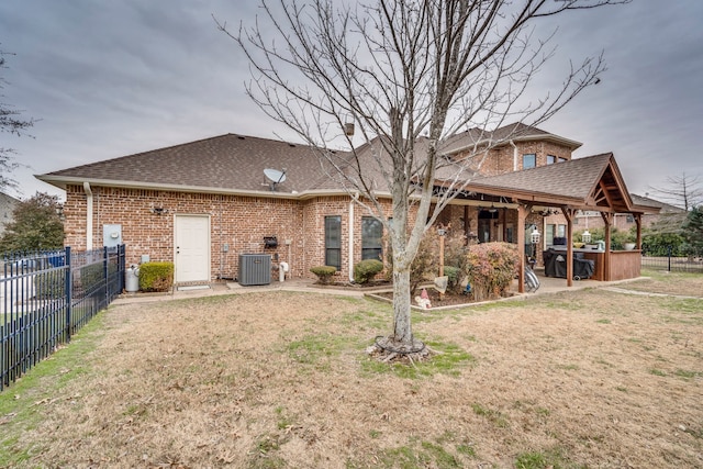 back of house with a patio area, central air condition unit, a jacuzzi, and a yard