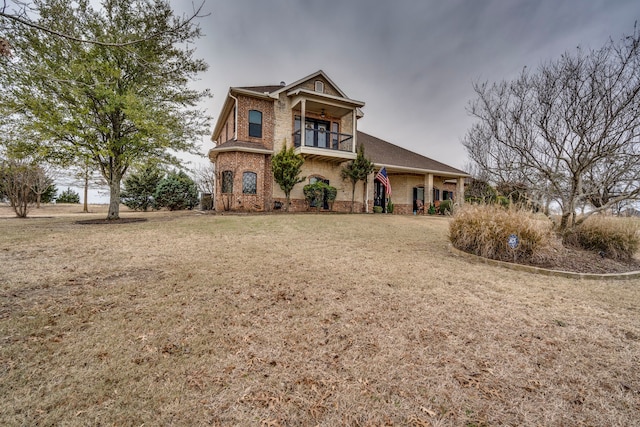 view of front facade with brick siding, stone siding, a front lawn, and a balcony