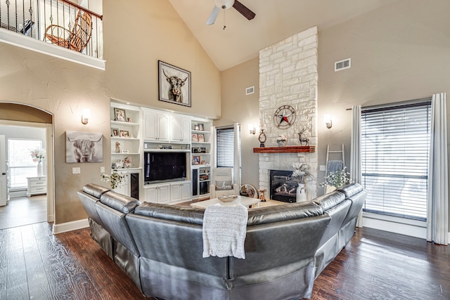 living area with high vaulted ceiling, a fireplace, a ceiling fan, visible vents, and dark wood-style flooring