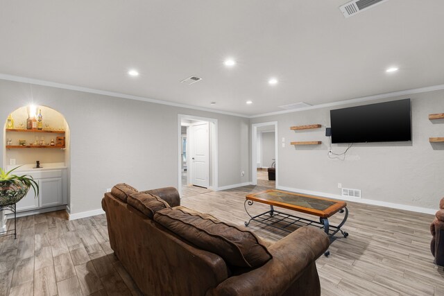 living room with light wood-type flooring and ornamental molding