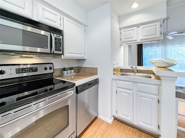 kitchen with light wood-type flooring, appliances with stainless steel finishes, white cabinetry, and kitchen peninsula