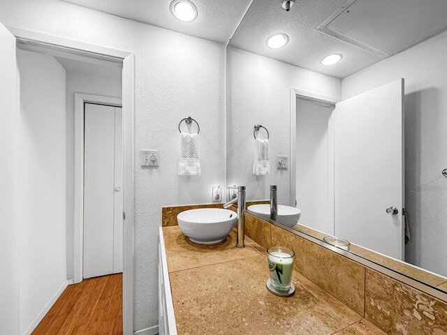 bathroom with a textured ceiling, vanity, and hardwood / wood-style flooring