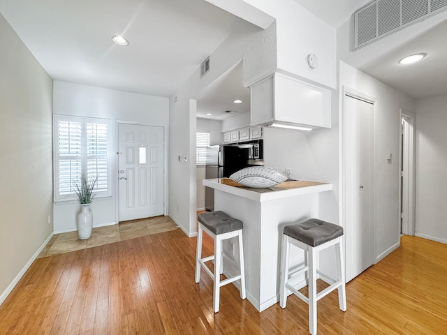 kitchen with a wealth of natural light, white cabinets, a kitchen bar, and kitchen peninsula